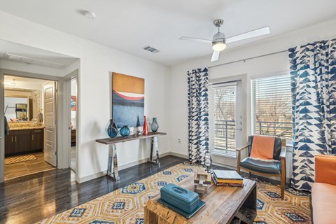 A living room with a rug, a chair, a table, and a painting on the wall.